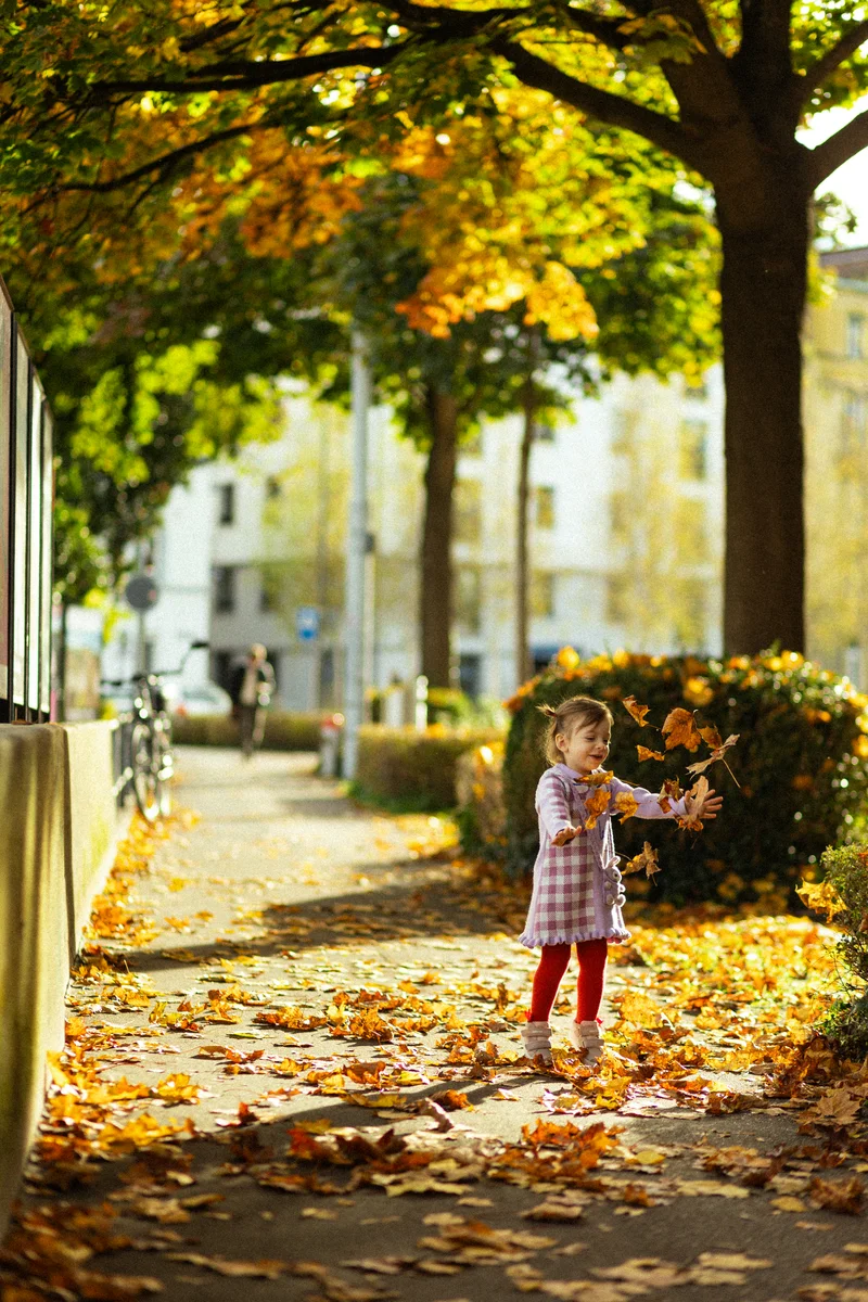 Baby Shooting Herbst – Kleinkind wirft Herbstblätter hoch im Stadtpark
