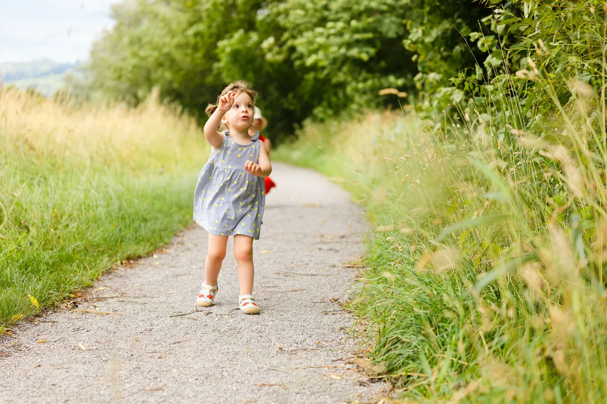 Kinderfotografie Outdoor – Kleinkind läuft auf Sommerweg durch die Natur