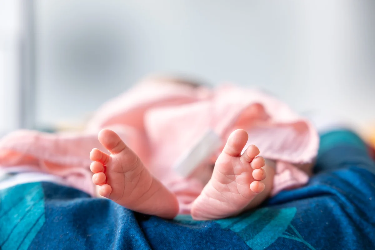 Neugeborenenfotografie Nahaufnahme – zarte Babyfüsschen auf bunter Decke