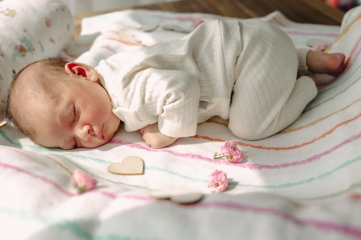 Neugeborenenfotografie – schlafendes Neugeborenes auf Decke mit Herz und Blumen