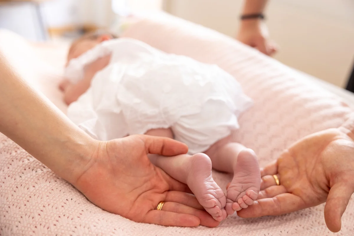 Neugeborenenfotografie – Babyfüsschen in Elternhänden mit Eheringen