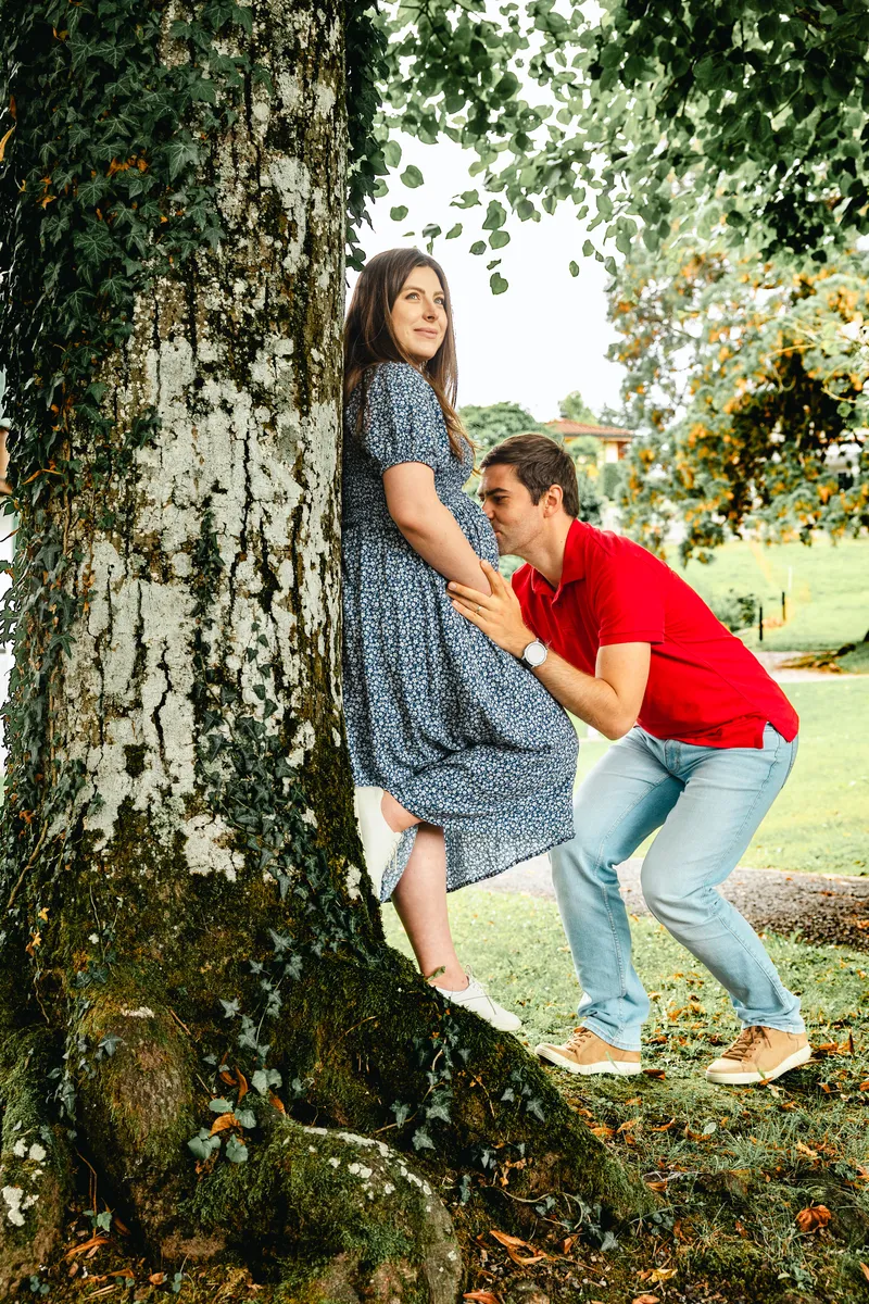 Babybauch Shooting Luzern – Mann küsst den Babybauch unter einem alten Baum