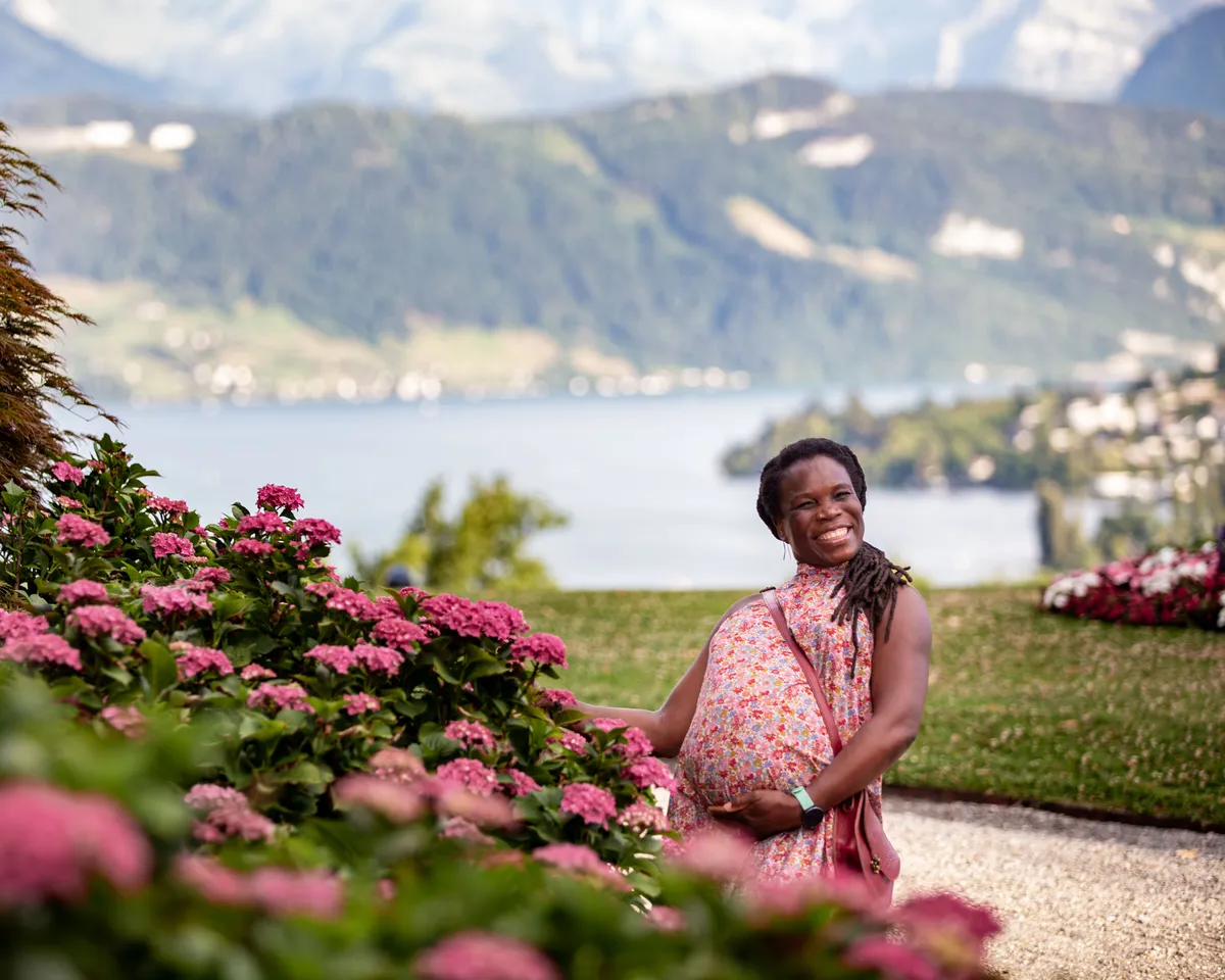 Babybauch Portrait Dreilindenpark – schwangere Frau riecht an rosa Hortensien am Vierwaldstättersee
