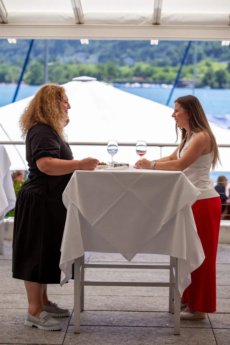 Networking auf der Seeterrasse des Grand Casino Luzern – zwei Frauen im Gespräch mit Blick auf den Vierwaldstättersee