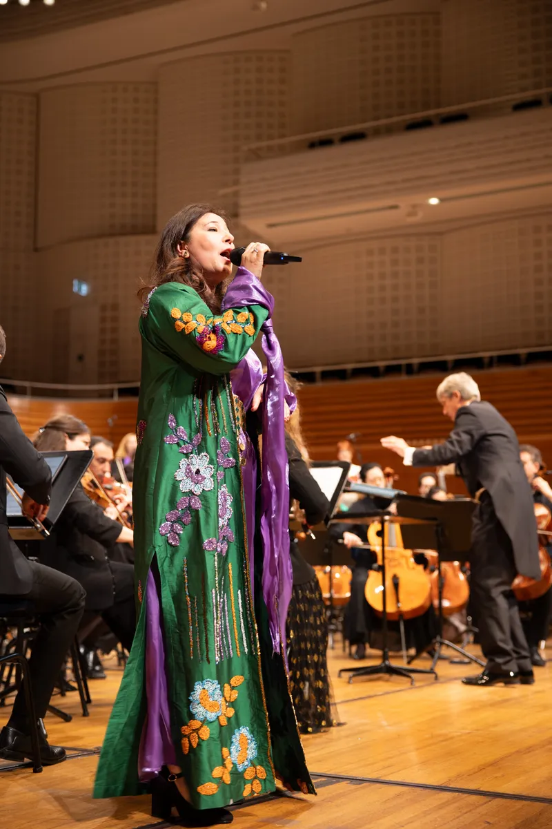 Solistin im bestickten grünen Kleid vor dem Orchester im KKL Luzern